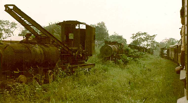 Guindaste ferroviário e locomotiva abandonados ao lado dos trilhos, ao longo do trajeto do antigo trem turístico