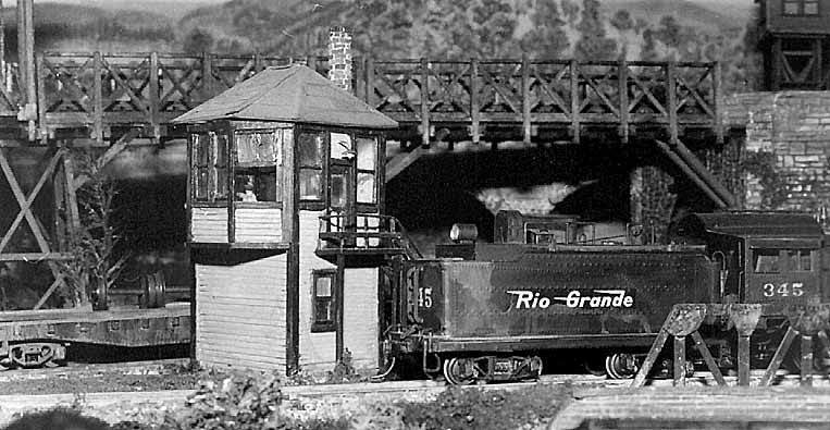 Vista da cabine de sinalização, tênder da locomotiva e ponte de madeira em treliça, na maquete